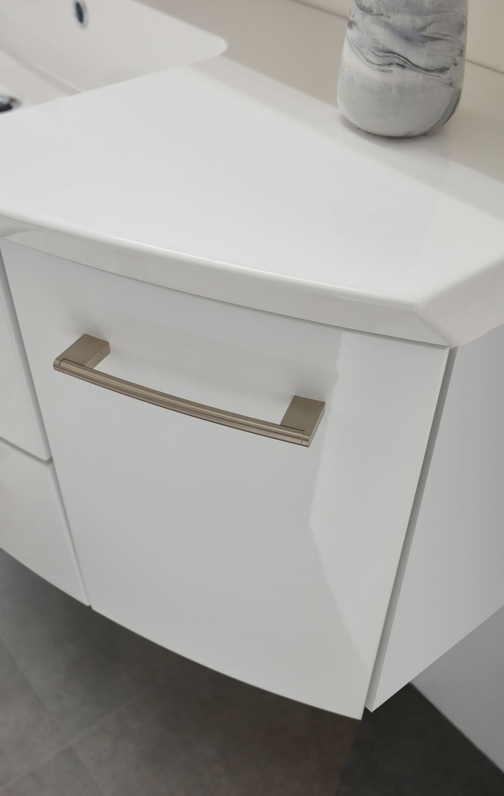 Nahaufnahme eines weißen Badezimmerschranks mit modernem Griff, von oben betrachtet.