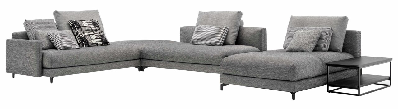 Graue Polsterrundecke mit mehreren gemusterten Kissen, abgebildet aus einer frontalen Perspektive. Rechts befindet sich ein schwarzer Beistelltisch.