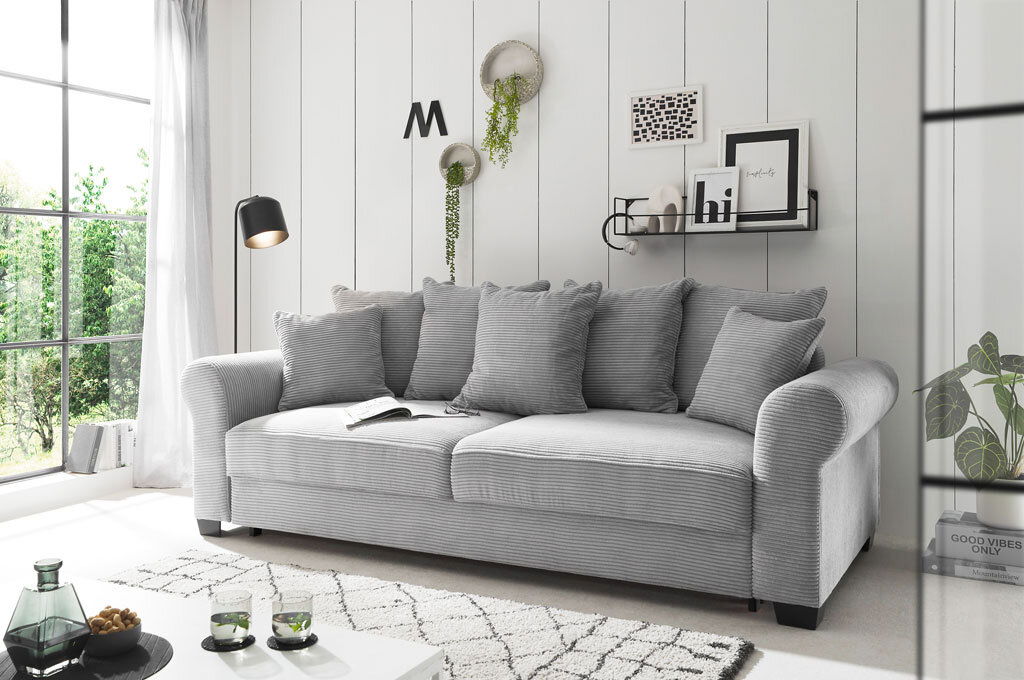 Hom´in Big Sofa MAUREEN Graues Funktionssofa mit mehreren Kissen in einem modernen Wohnzimmer, seitliche Perspektive.
