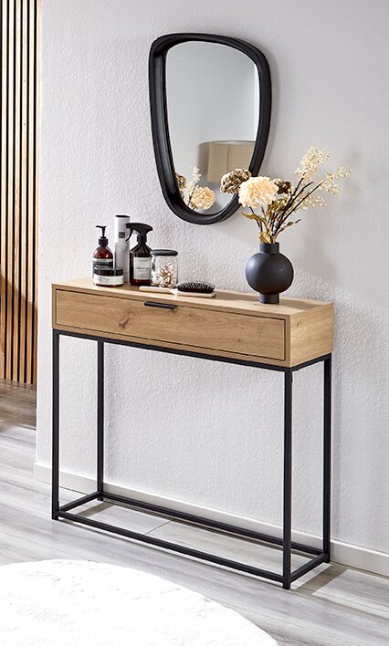 Schmale Flurkonsole aus hellem Holz mit schwarzem Metallgestell und Schublade, dekoriert mit Vase und Pflegeprodukten, frontale Perspektive leicht von links