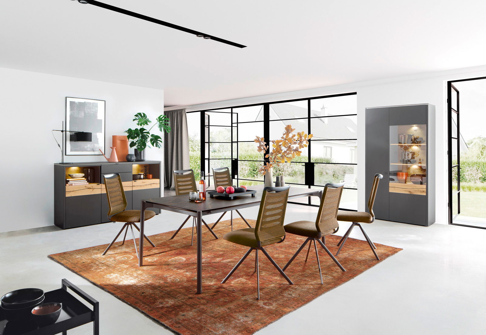 Venjakob Sessel LILLI 3000 Moderner Essbereich mit Esstisch und Stühlen auf einem roten Teppich, umgeben von großen Fenstern mit Blick ins Grüne, aus einer seitlichen Perspektive fotografiert.