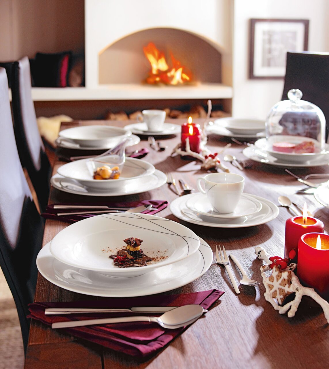 Een feestelijk gedekte tafel met wit servies, kaarsen en een open haard op de achtergrond, gezien vanuit de zijkant.