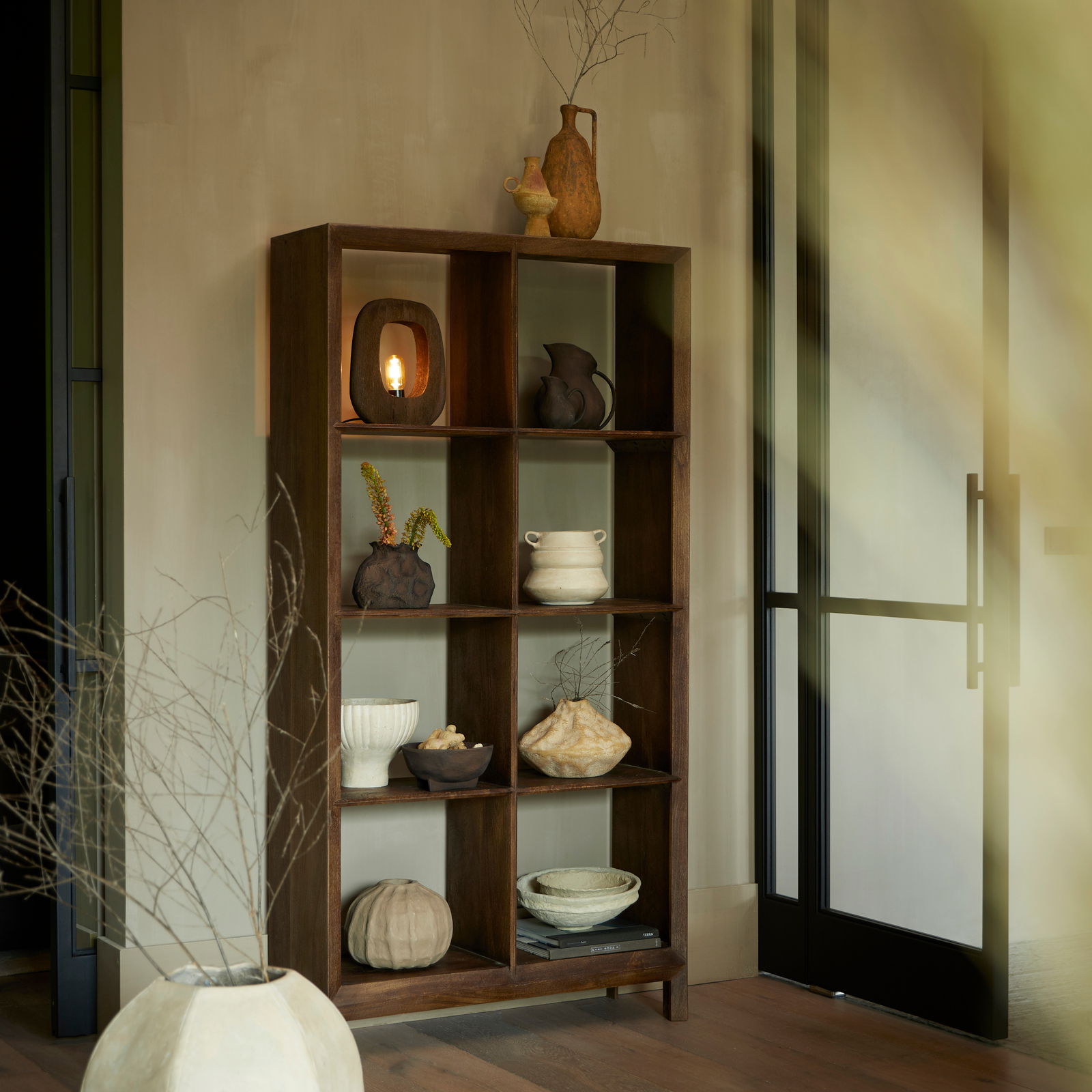 Standregal SONDRI aus Holz mit neun Fächern, dekoriert mit Keramikvasen und Schalen, in einem modernen Raum mit natürlichem Licht, seitliche Perspektive.