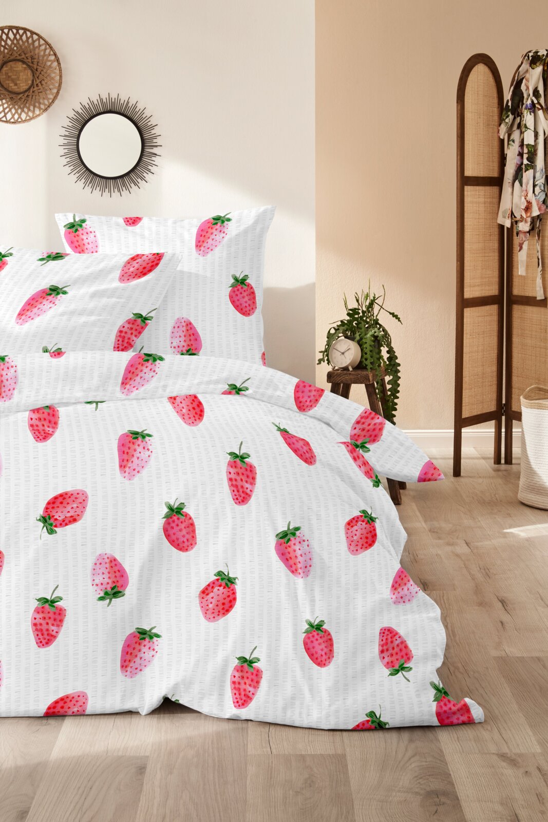 Primera Bettwäsche Bettwäsche-Set mit Erdbeer-Muster auf weißem Hintergrund, frontal in leicht seitlicher Perspektive auf einem gemachten Bett im hellen Schlafzimmer