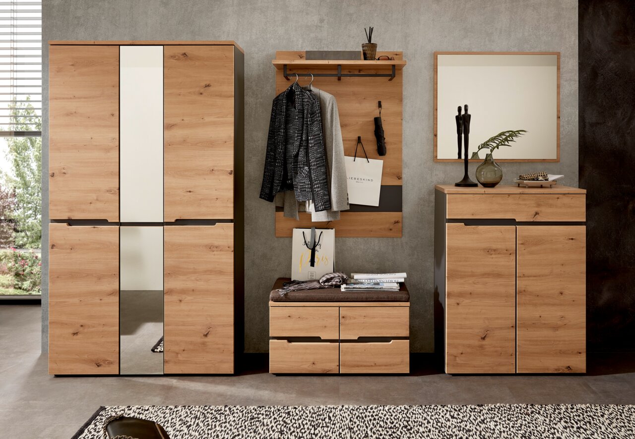 Garderoben-Set aus Holz in moderner Optik, bestehend aus einem großen Schrank mit Spiegel, einer Wandgarderobe mit Haken und Ablage, einer Sitzbank mit Schubladen und einem Spiegel, aus der Frontalperspektive betrachtet.