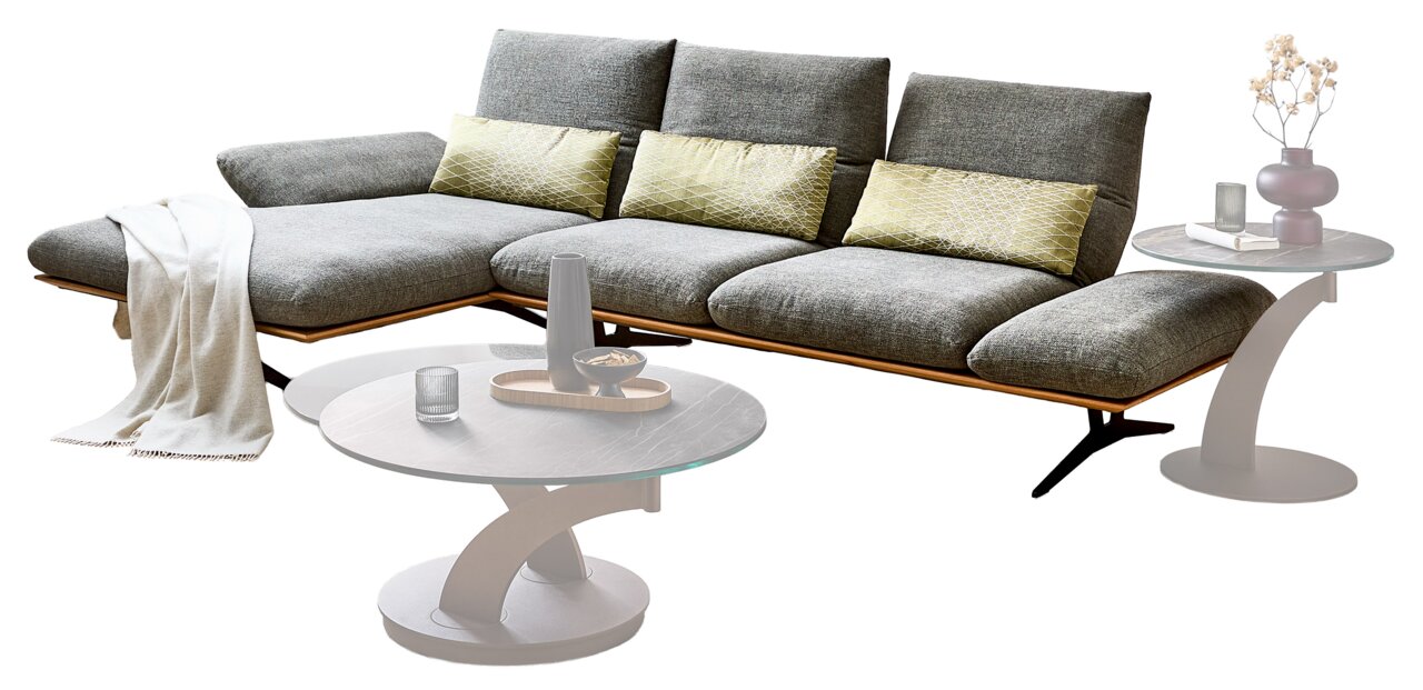 Dieter Knoll Longchairkombination FORMIA Modernes graues Lounge-Sofa mit verstellbaren Rückenlehnen, Holzsockel und Zierkissen, daneben runde Couchtische; Ansicht schräg von vorne.