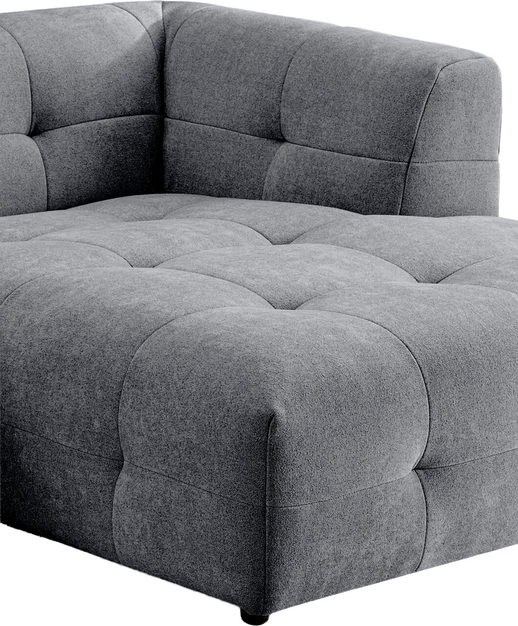 Graues, gepolstertes Lounge-Sofa/Modulsofa mit gesteppter Sitzfläche und Rückenlehne, Detailansicht aus schräger Vorderseiten-Perspektive vor weißem Hintergrund