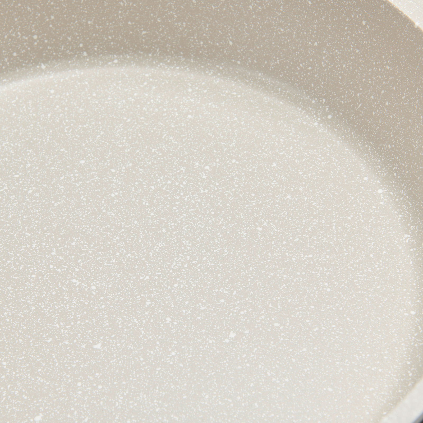 Nahaufnahme einer hellen, gesprenkelten Oberfläche eines Kochtopfs.