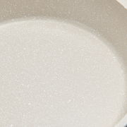 Nahaufnahme einer hellen, gesprenkelten Oberfläche eines Kochtopfs.