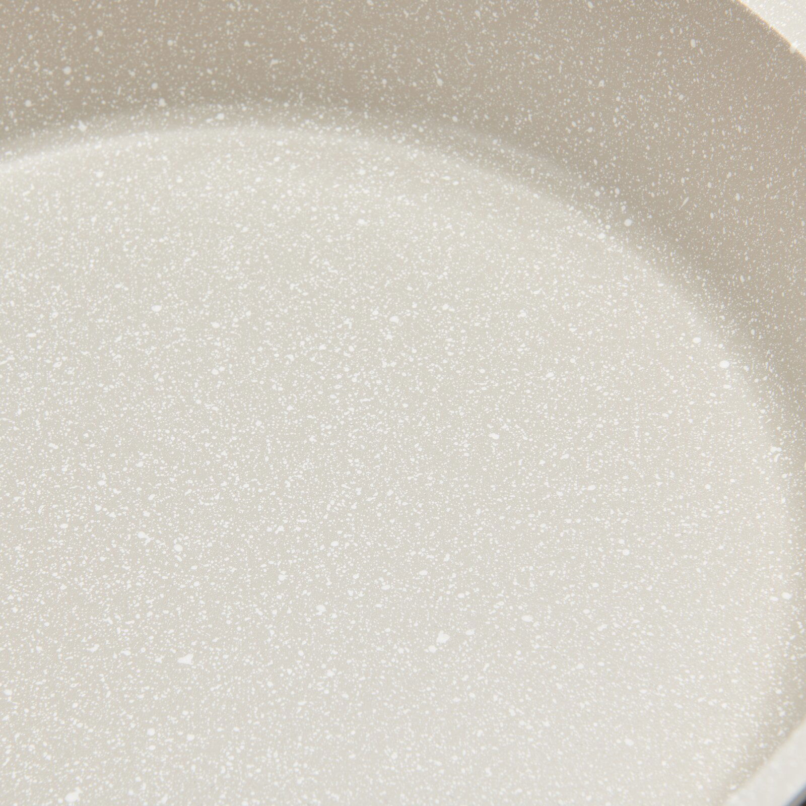 Nahaufnahme einer hellen, gesprenkelten Oberfläche eines Kochtopfs.