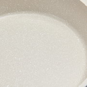 Nahaufnahme einer hellen, gesprenkelten Oberfläche eines Kochtopfs.