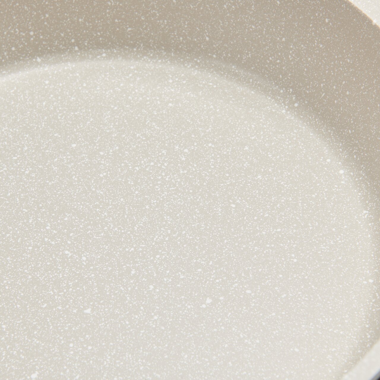 Nahaufnahme einer hellen, gesprenkelten Oberfläche eines Kochtopfs.