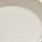 Nahaufnahme einer hellen, gesprenkelten Oberfläche eines Kochtopfs.