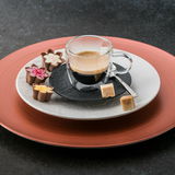 Espresso Glas 60ml auf einem Teller mit Pralinen und Zuckerwürfeln, seitliche Perspektive