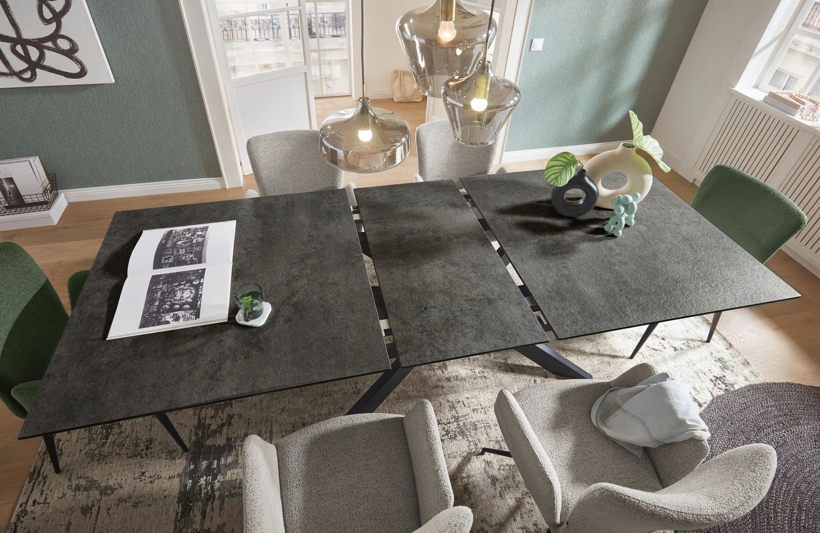 Moderner Esstisch mit dunkler Tischplatte, umgeben von stilvollen Stühlen, aus der Vogelperspektive fotografiert.