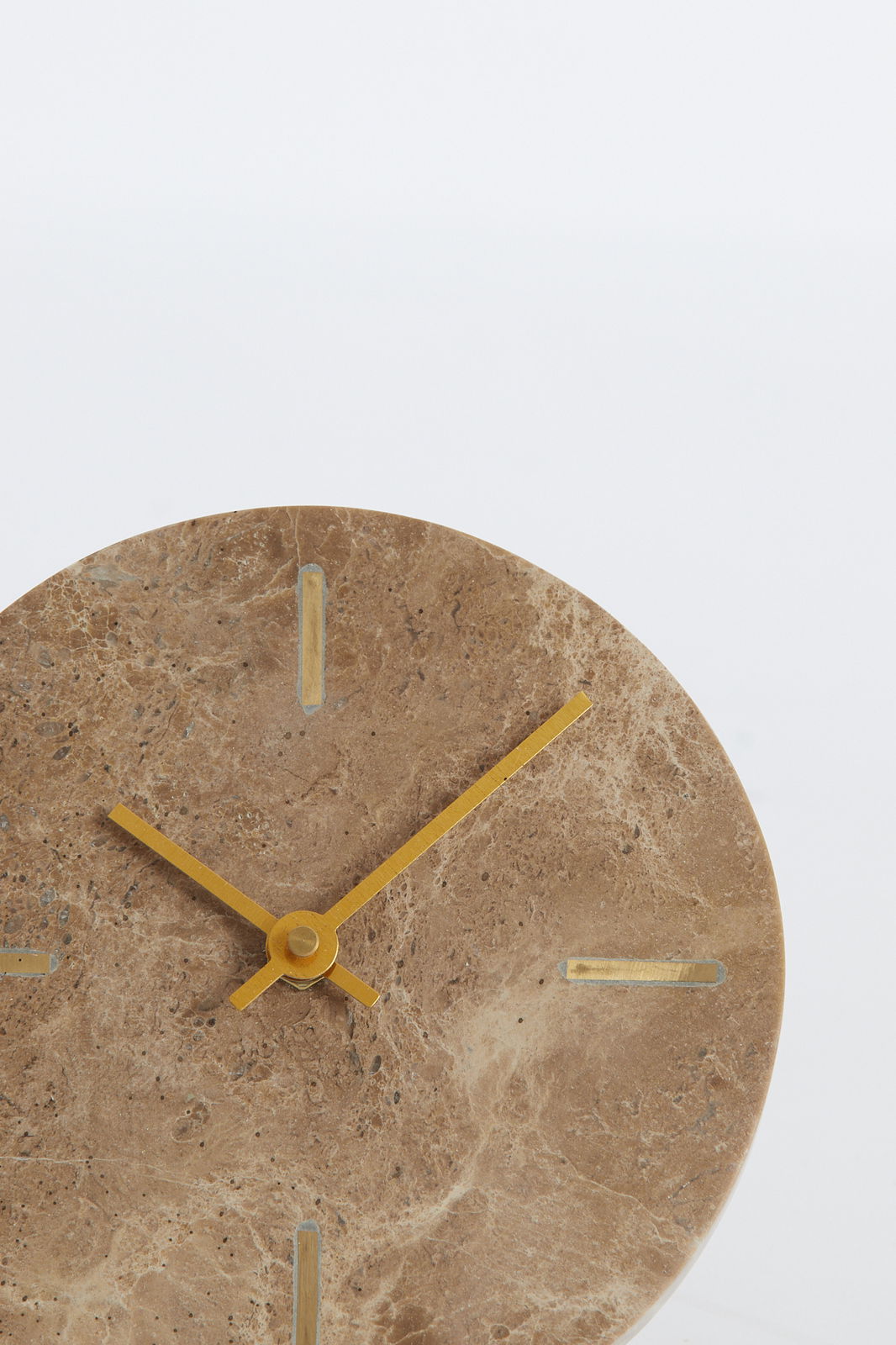 Nahaufnahme einer runden Uhr aus braunem Marmor mit goldenen Zeigern und Markierungen, frontal betrachtet.