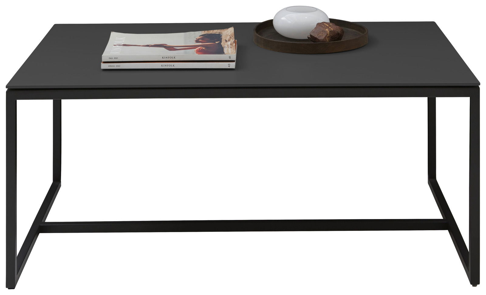 Dieter Knoll Couchtisch RINA Moderner Couchtisch mit schwarzer Tischplatte, darauf liegen Zeitschriften und eine dekorative Schale mit einem Stein, frontal betrachtet.