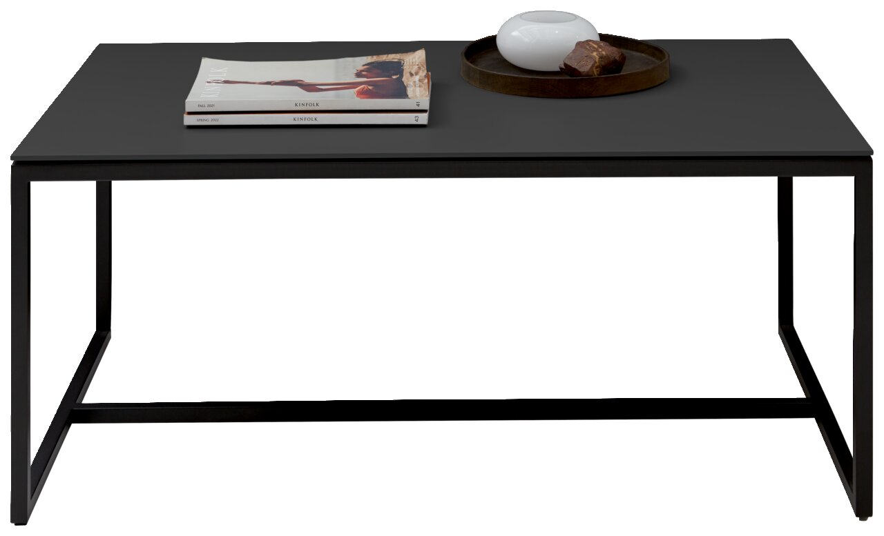Moderne salontafel met een zwart tafelblad, waarop tijdschriften en een decoratieve schaal met een steen liggen, gezien vanaf de voorkant.