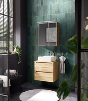 Moderner Waschtischunterschrank aus Holz mit zwei Schubladen, montiert an einer Wand mit grünen Fliesen, frontal betrachtet.