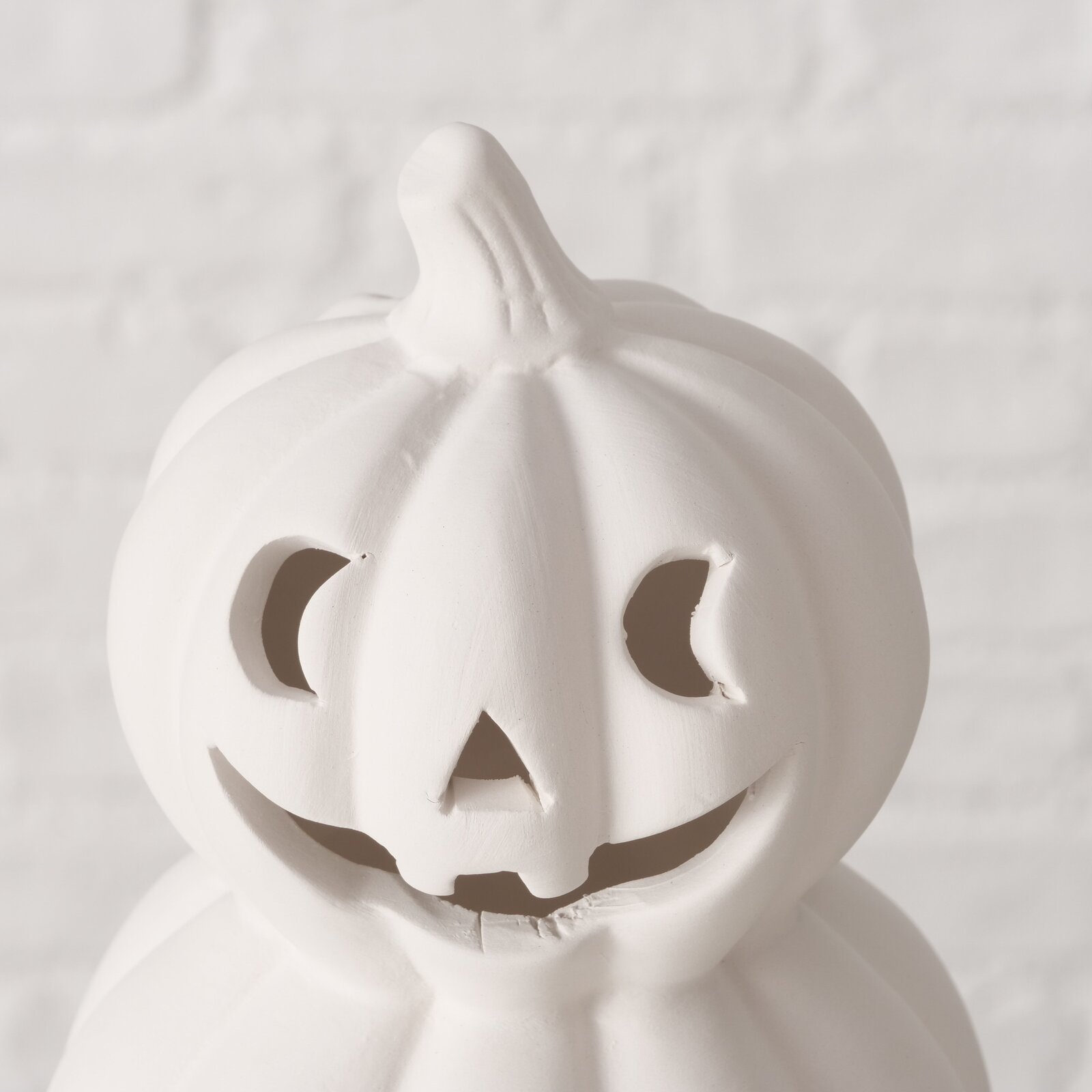 Weißer Teelichthalter in Form eines Kürbisses mit geschnitztem Gesicht, Frontalansicht