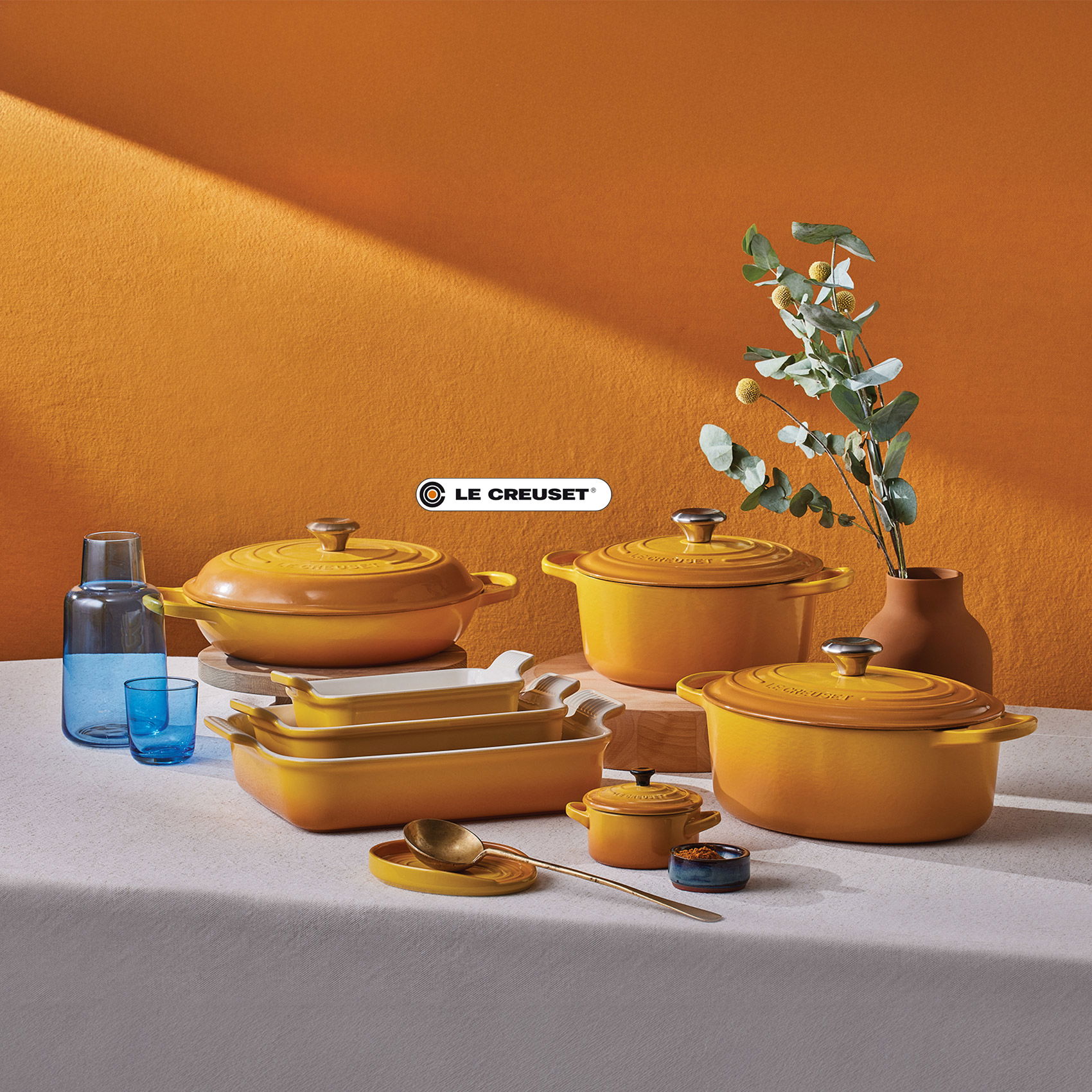Le-Creuset Gusseisen-Töpfe und Auflaufformen in Gelb-Orange auf gedecktem Tisch