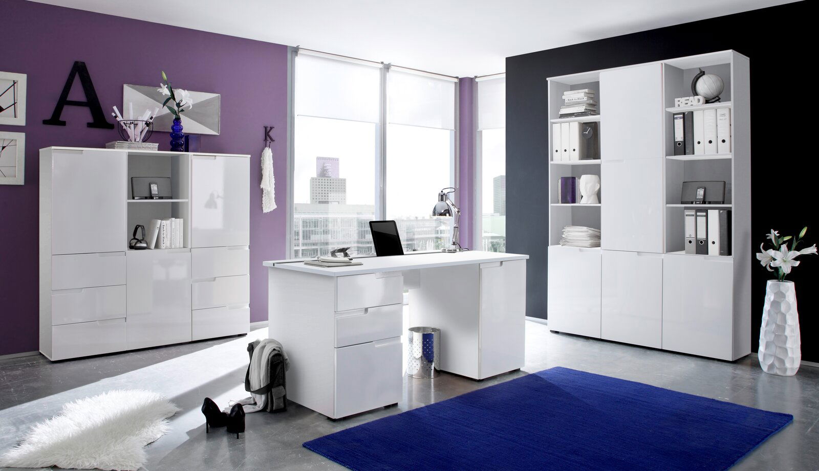 BOXXX Regal hoch SILAS Moderne Büromöbel in einem stilvollen Raum mit lila und schwarzer Wand, bestehend aus einem weißen Schreibtisch und zwei weißen Regalen, seitliche Perspektive.