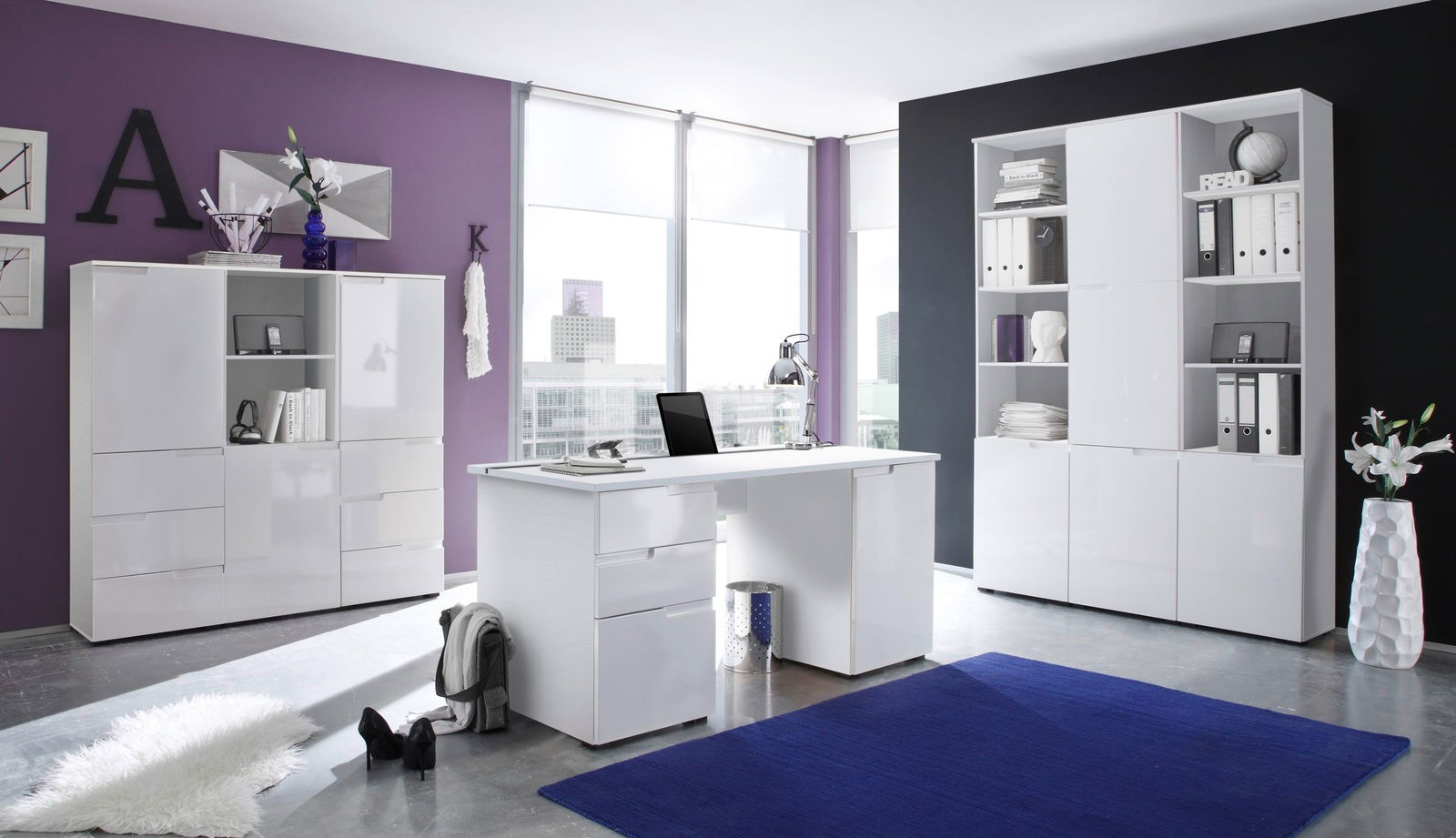 Moderne Büromöbel in einem stilvollen Raum mit lila und schwarzer Wand, bestehend aus einem weißen Schreibtisch und zwei weißen Regalen, seitliche Perspektive.
