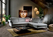 Graue Eckgarnitur in modernem Wohnzimmer, seitliche Perspektive, mit dekorativen Kissen und Couchtisch auf Teppich.