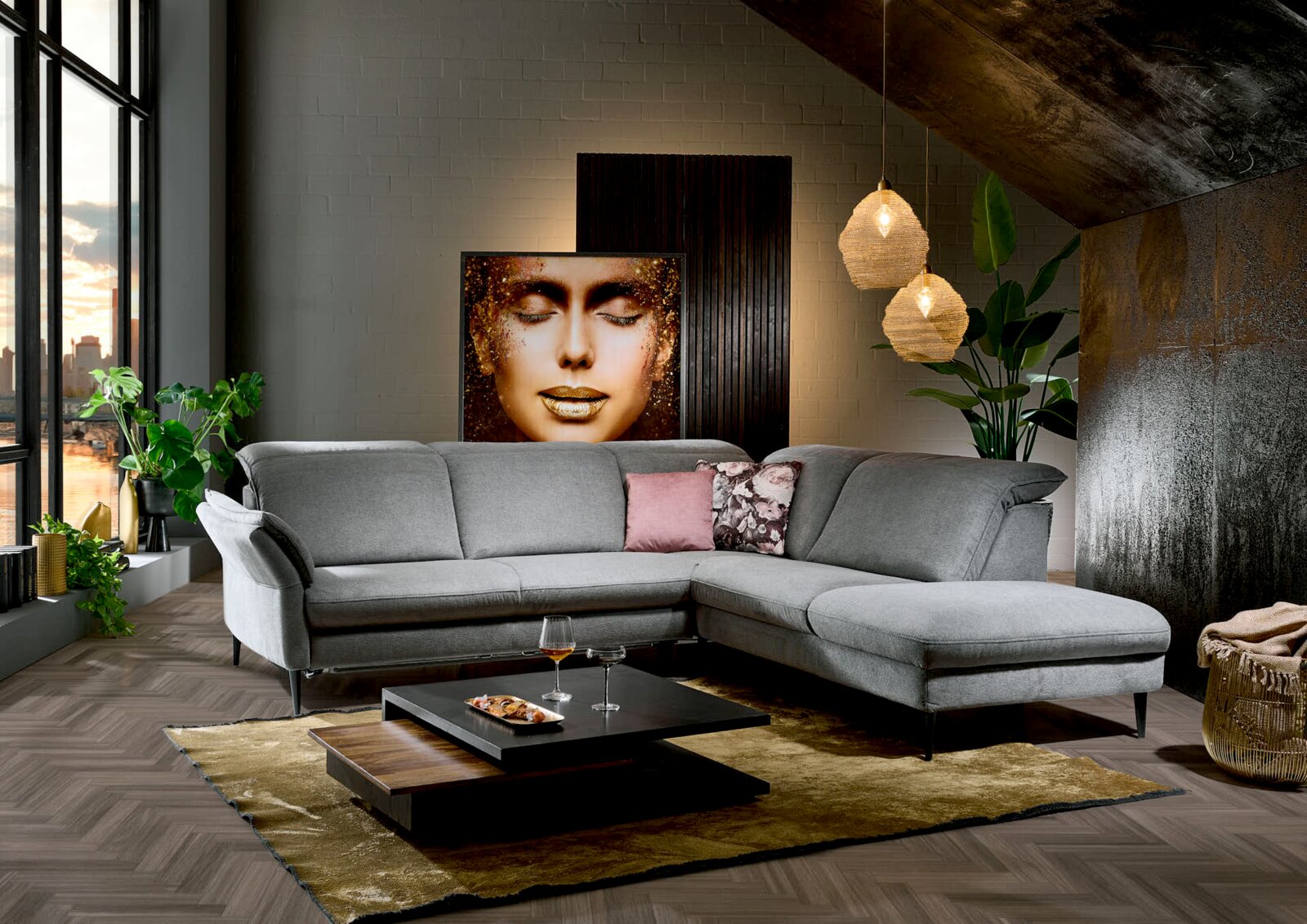 Graue Eckgarnitur in modernem Wohnzimmer, seitliche Perspektive, mit dekorativen Kissen und Couchtisch auf Teppich.