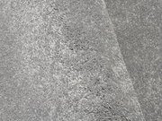 Nahaufnahme eines grauen Uni-Teppichs mit weicher, flauschiger Textur, perspektivisch von der Seite aufgenommen.