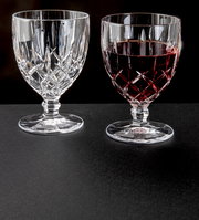 Zwei Weinkelche Noblesse 350ml aus Kristallglas, einer leer und einer mit Rotwein gefüllt, auf schwarzem Untergrund, seitliche Perspektive.