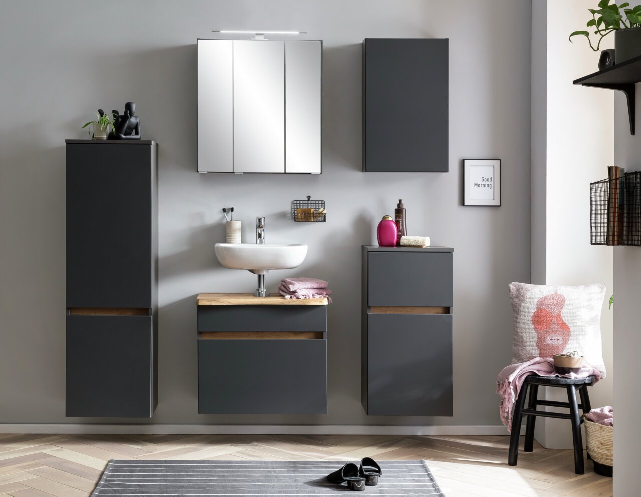 Moderne Badezimmermöbel in dunklem Grau, bestehend aus Hängeschränken und einem Waschbeckenunterschrank, frontal betrachtet.