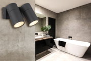 Moderne schwarze Außenwandleuchte mit zwei zylindrischen Strahlern, montiert an einer Betonwand in einem stilvollen Badezimmer. Perspektive von der Seite.