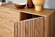 Nahaufnahme eines modernen Sideboards aus Holz mit geöffneter Tür, dekoriert mit Schalen und Vasen, aus seitlicher Perspektive.