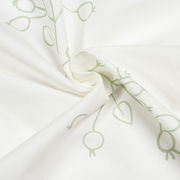 Nahaufnahme eines weißen Schals mit grünem, abstraktem Muster, in einer spiralförmigen Anordnung drapiert.