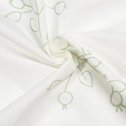 Nahaufnahme eines weißen Schals mit grünem, abstraktem Muster, in einer spiralförmigen Anordnung drapiert.