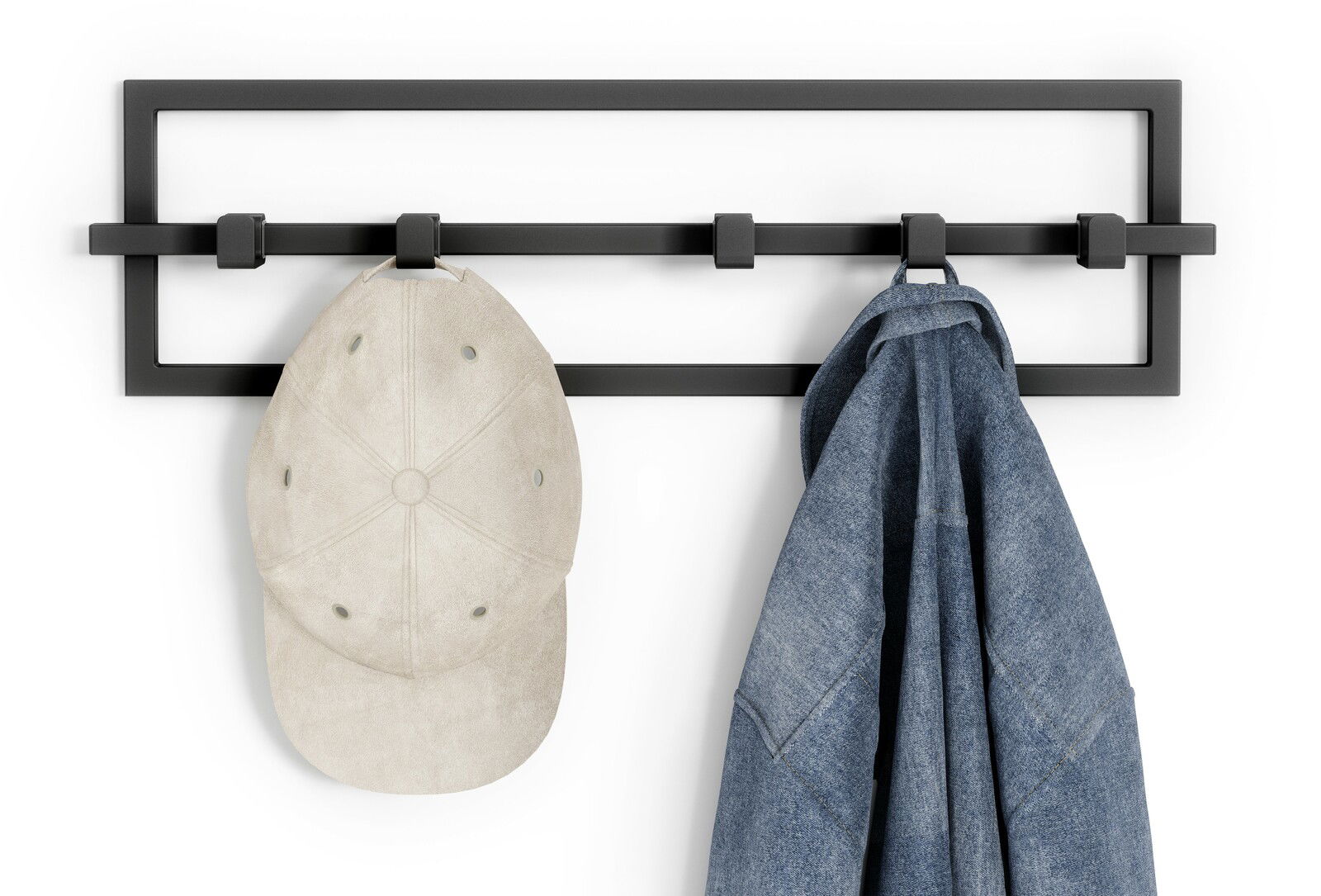 Schwarze Wandgarderobe mit vier Haken, an denen eine beige Kappe und eine blaue Jeansjacke hängen, frontal betrachtet.
