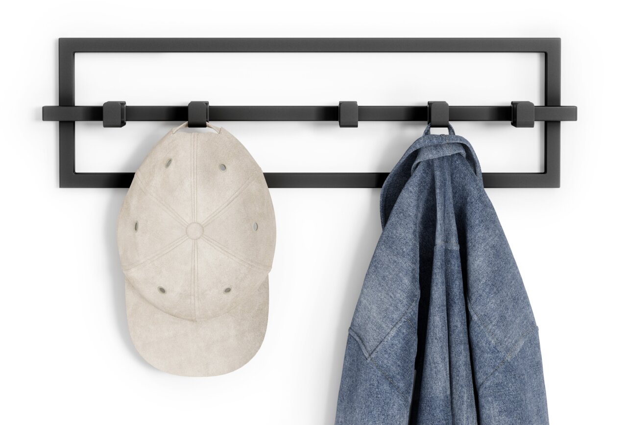 Schwarze Wandgarderobe mit vier Haken, an denen eine beige Kappe und eine blaue Jeansjacke hängen, frontal betrachtet.