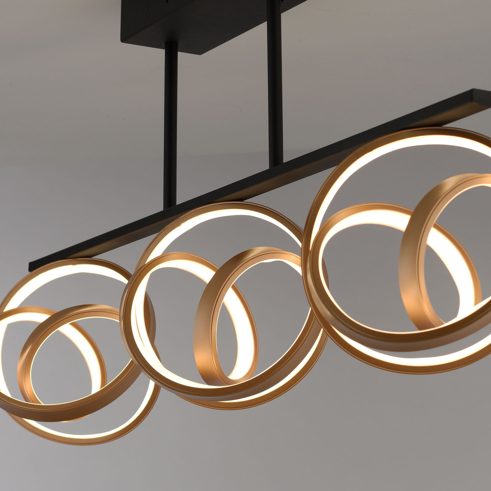 Moderne Deckenleuchte mit goldenen, ineinander verschlungenen Ringen, seitliche Perspektive