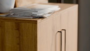 Nahaufnahme eines niedrigen Schuhschranks aus Holz mit modernen Griffen, von oben fotografiert.