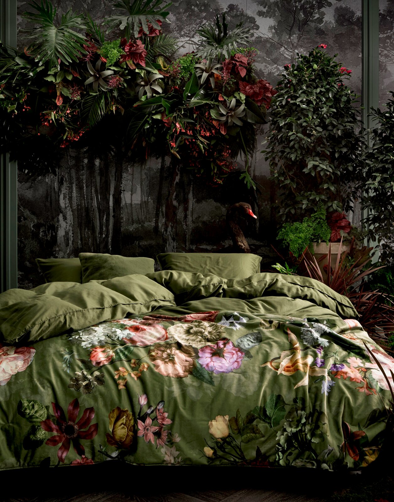 Beddengoedset met een weelderig, botanisch ontwerp met bloemmotieven op een groene achtergrond, gefotografeerd vanuit een rechtvooruit perspectief.