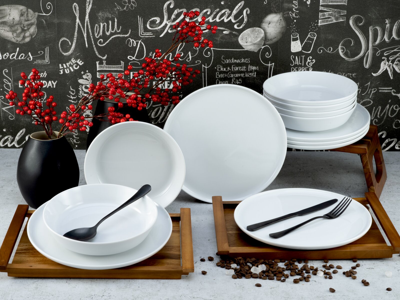 Creatable Tafelservice 12-tlg CHEF COLLECTION Weißes Porzellan-Geschirrset mit Tellern und Schalen auf Holztabletts, dekoriert mit schwarzem Besteck und roten Beerenzweigen, frontal in leicht erhöhter Perspektive fotografiert.
