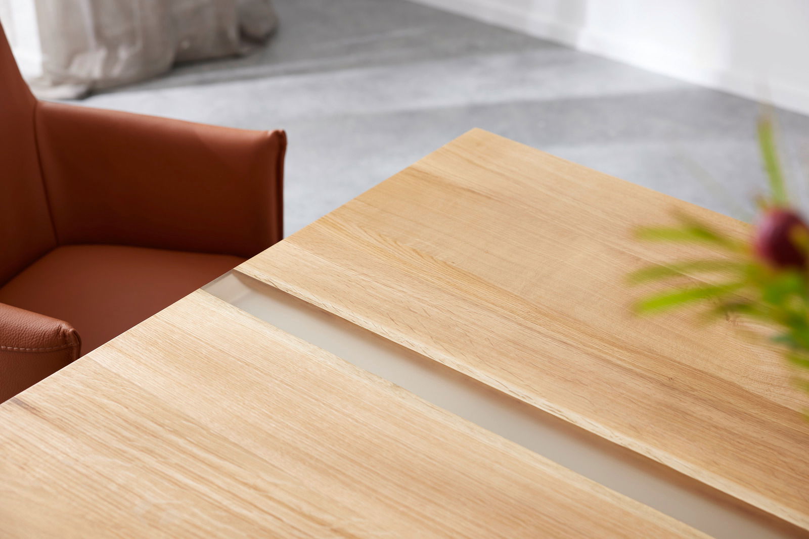 Musterring Esstisch MR NILAN Nahaufnahme eines Esstisches aus hellem Holz mit einem braunen Stuhl im Hintergrund, aus der Vogelperspektive fotografiert.