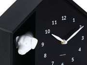 Schwarze Wanduhr mit weißem Hundekopf und weißen Zeigern, seitliche Perspektive