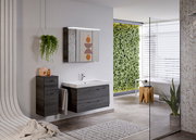 Moderner Badblock mit dunklen Holzschränken und Waschbecken, seitliche Perspektive, umgeben von stilvoller Dekoration und Pflanzen.