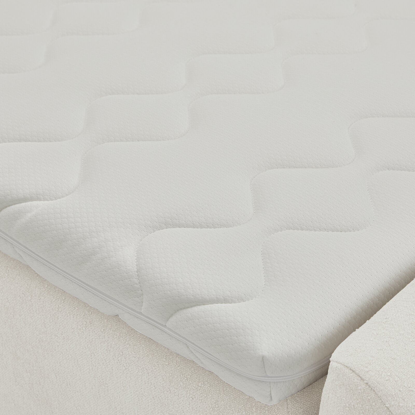 Nahaufnahme einer weißen Matratze mit wellenförmigem Muster auf einem Boxbett.