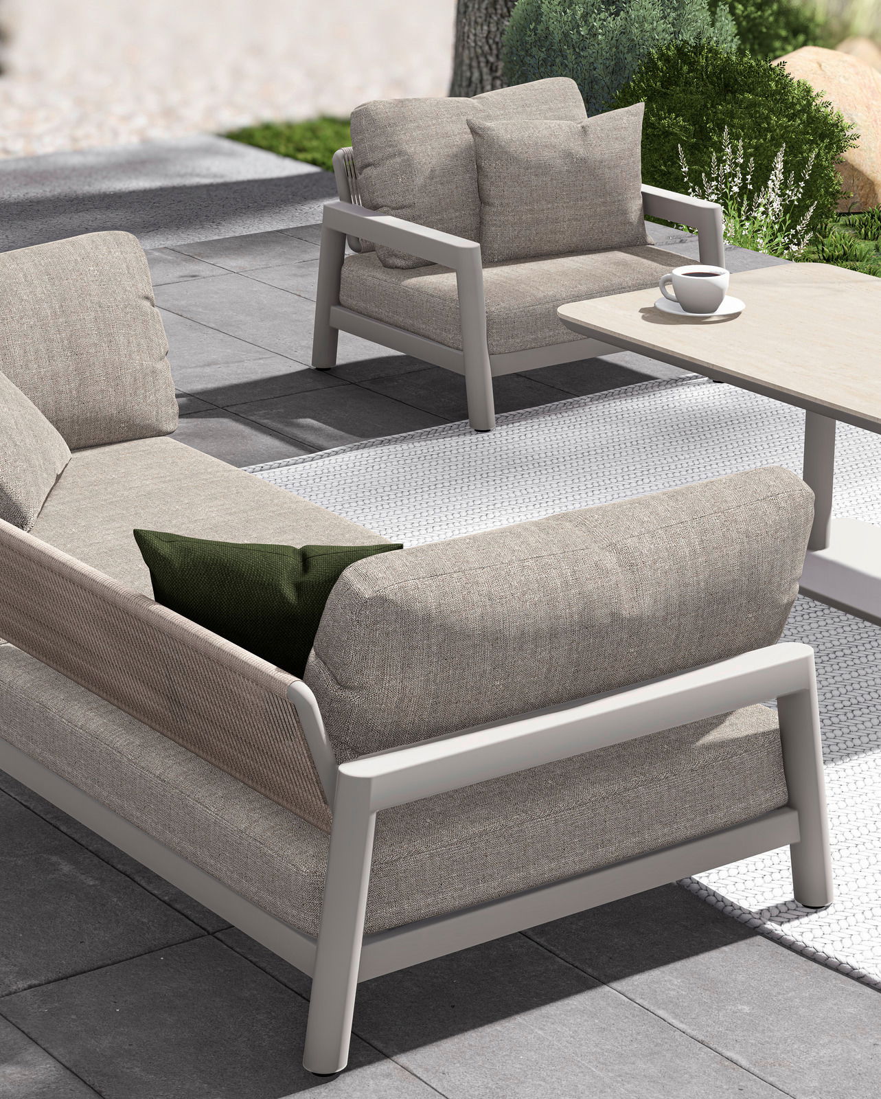 Modernes Loungesofa und Sessel auf einer Terrasse, seitliche Perspektive, mit bequemen Kissen und einem Tisch mit Kaffeetasse.