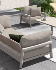 Modernes Loungesofa und Sessel auf einer Terrasse, seitliche Perspektive, mit bequemen Kissen und einem Tisch mit Kaffeetasse.