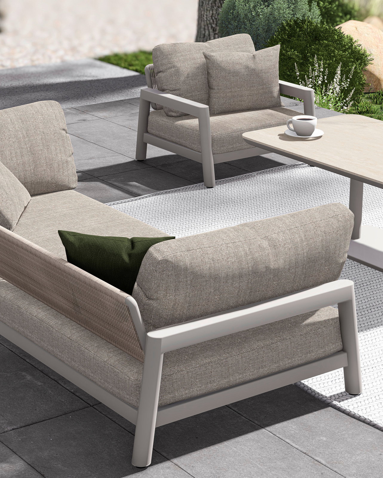 Modernes Loungesofa und Sessel auf einer Terrasse, seitliche Perspektive, mit bequemen Kissen und einem Tisch mit Kaffeetasse.