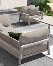 Modernes Loungesofa und Sessel auf einer Terrasse, seitliche Perspektive, mit bequemen Kissen und einem Tisch mit Kaffeetasse.